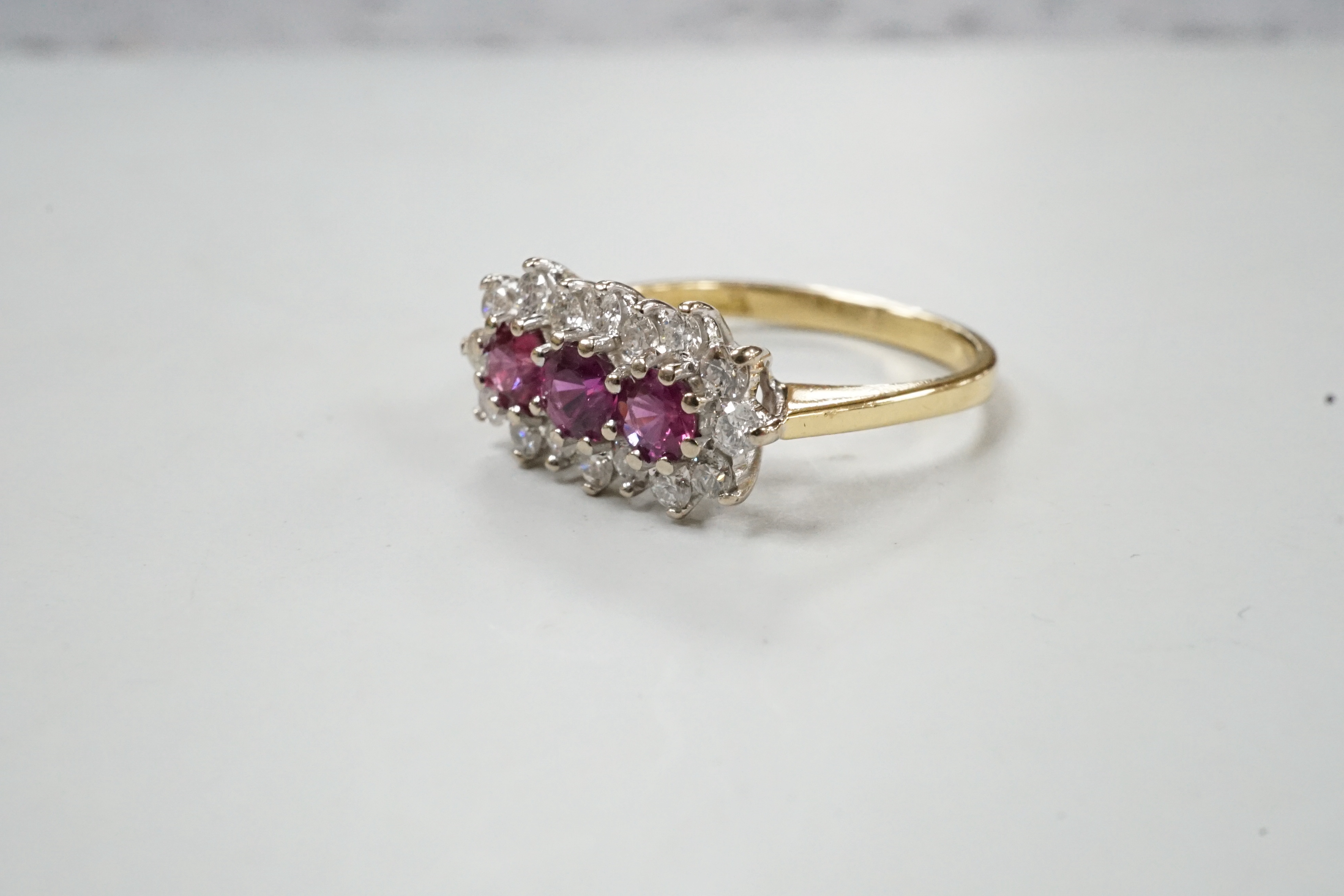 A modern 18ct gold, ruby and diamond set triple cluster ring, size L, gross weight 3.3 grams.